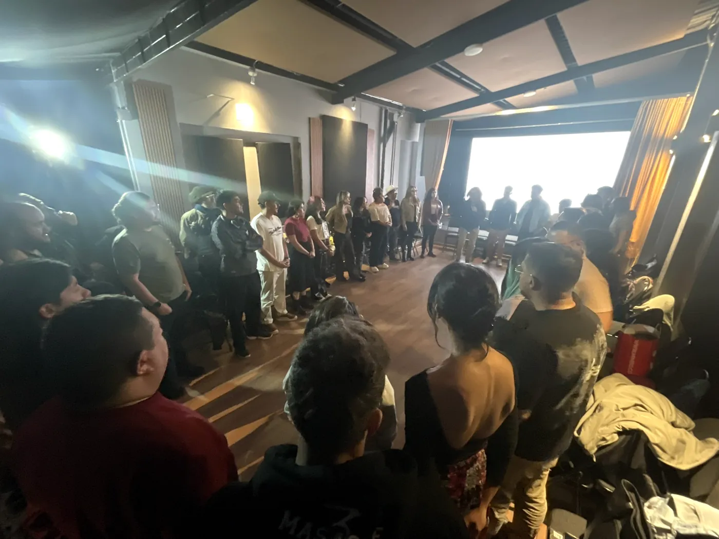 Asistentes de pie en círculo en la sala principal de Casa A Voz Estudios